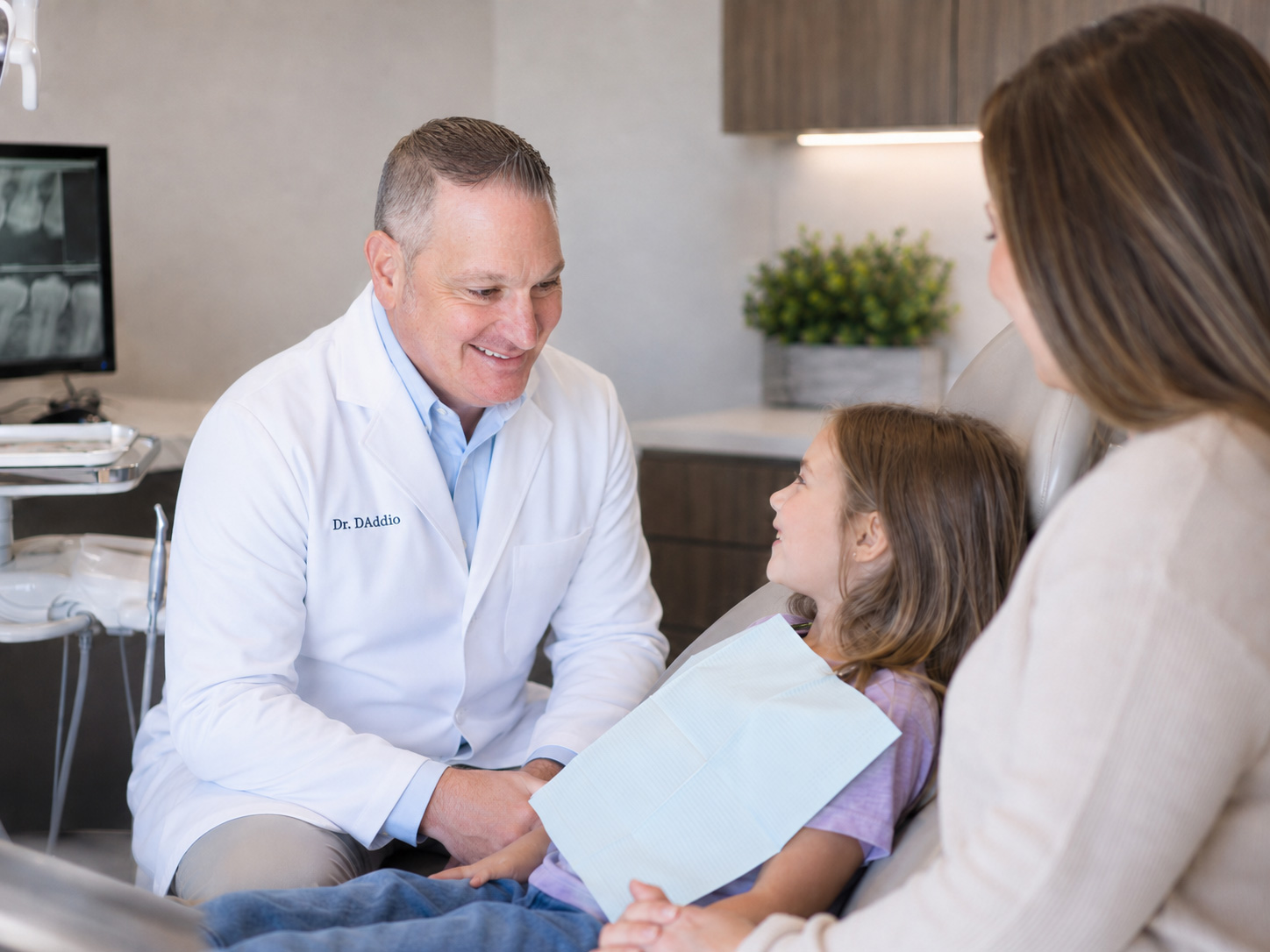 Dr. D'Addio talking with a young patient and her mother, answering common questions about family dental care at Dunning Family Dental.